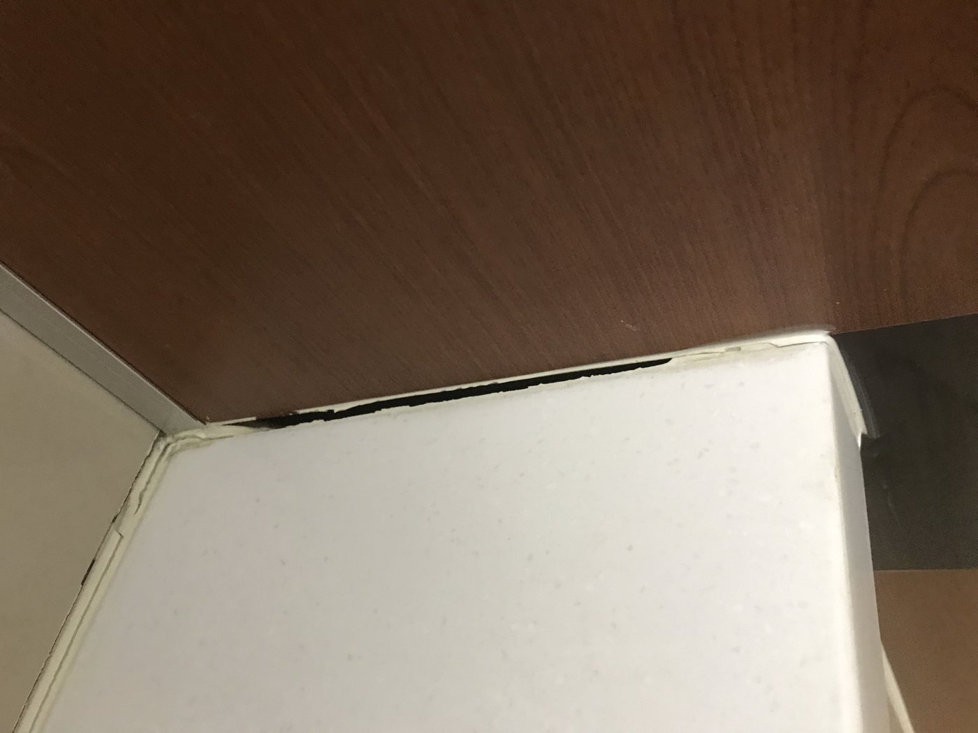櫃體與檯面接縫的填縫已與材料分離、開出黑縫，屬黏著不良。