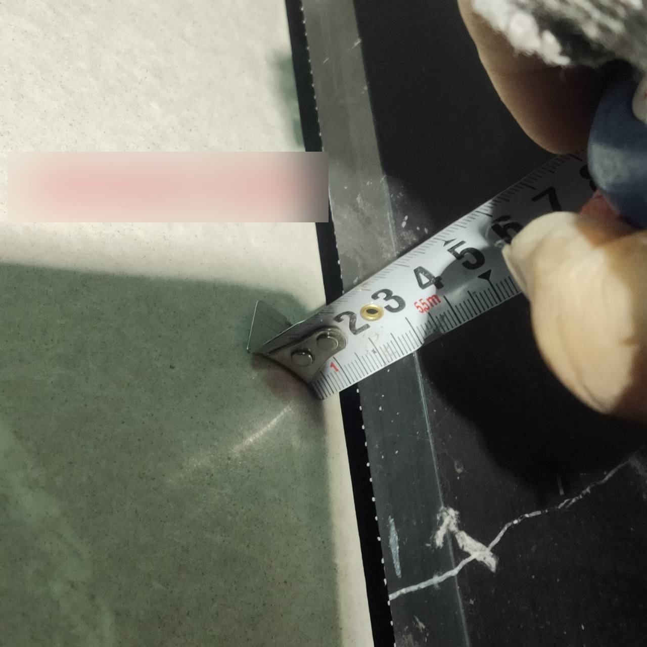 某新完工大樓公共區域石材收邊：以捲尺量測可見明顯空洞縫隙（樓層標註已模糊）。